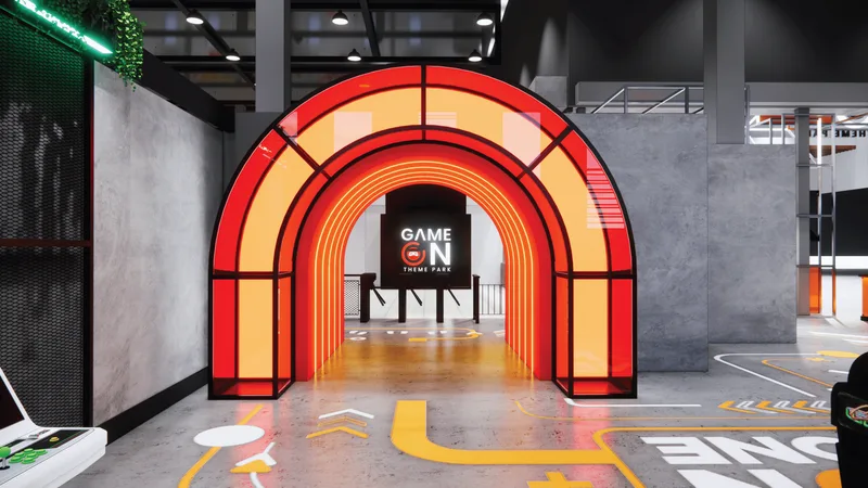 A red and orange illuminated archway entrance to GAMEON Theme Park, the "GAME ON THEME PARK" sign glowing through the arch, above a polished concrete floor marked with yellow wayfinding lines